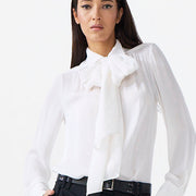 Woman wearing a white blouse with a bow tie and black pants on a white background