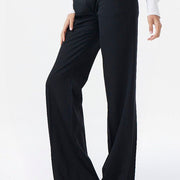 Woman wearing a white blouse and black pants on a white background