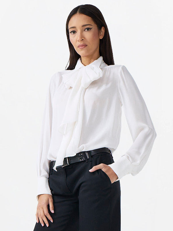 Woman wearing a white blouse and black pants on a white background